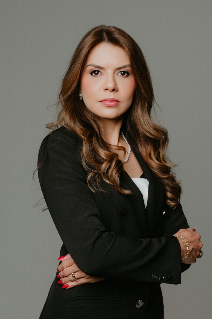 Tayanne Martins, de terno preto, com braços cruzados